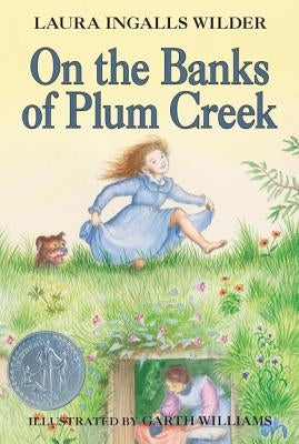 Paperback of "On the Banks of Plum Creek" by HarperCollins, showing the book cover with rural landscape illustration.