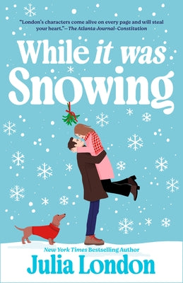 Paperback copy of "While It Was Snowing" by Penguin Publishing Group, showing the book cover with snowy winter scene.