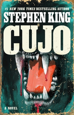 Paperback copy of "Cujo" by Scribner Book Company featuring a close-up of the book cover with bold title and author details.