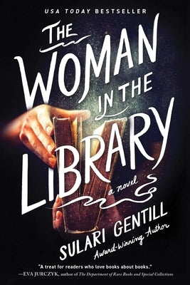 Paperback copy of "The Woman in the Library" by Poisoned Pen Press, featuring a book cover with an illustration of a woman in a library.