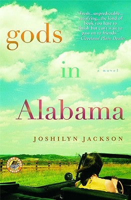 Paperback copy of "Gods in Alabama" by Grand Central Publishing featuring the book cover with title and author details.