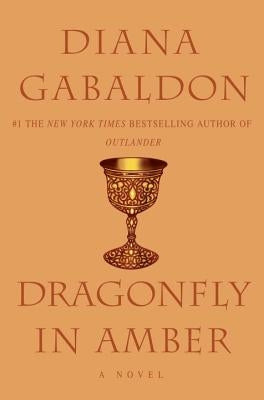 Paperback copy of "Dragonfly in Amber" by Delta, featuring the book cover with a dragonfly illustration.