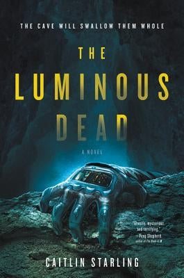 Paperback copy of The Luminous Dead novel by Harper Voyager, featuring the book's cover with dark and luminous design elements.
