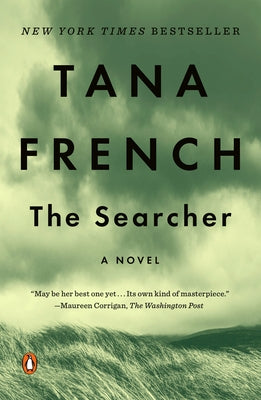 Paperback copy of "The Searcher" by Penguin Books featuring a cover image with abstract artwork and book title.