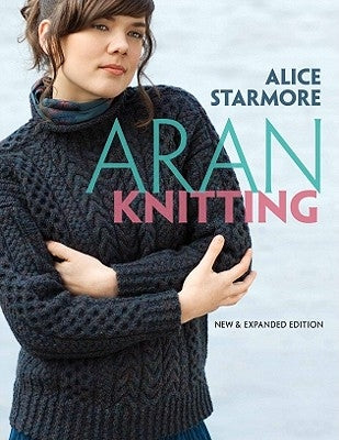 Open paperback copy of Aran Knitting book by Dover Publications featuring detailed patterns and illustrations.