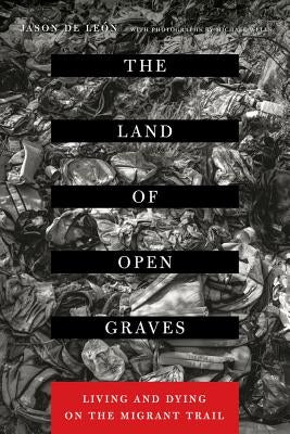 Paperback book titled "The Land of Open Graves" by University of California Press, featuring a cover with desert imagery and migrants.