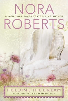 Holding the paperback novel "Holding the Dream" by Berkley Books, with a colorful cover and clear title visible.